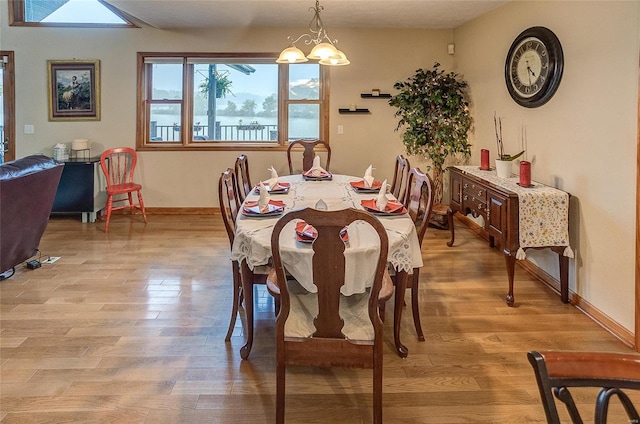 dining space with light wood-type flooring and an inviting chandelier