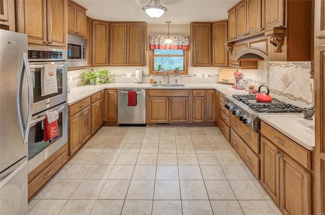 kitchen featuring appliances with stainless steel finishes, hanging light fixtures, sink, light tile patterned floors, and decorative backsplash