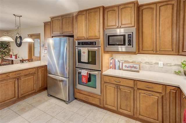 kitchen with light tile patterned floors, decorative backsplash, stainless steel appliances, and decorative light fixtures