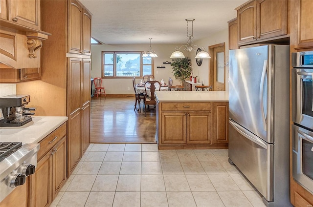 kitchen featuring a notable chandelier, stainless steel appliances, hanging light fixtures, and light hardwood / wood-style floors