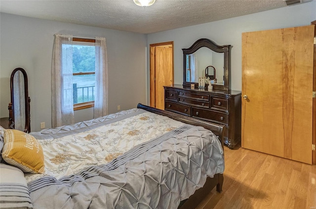 bedroom with light hardwood / wood-style flooring and a textured ceiling