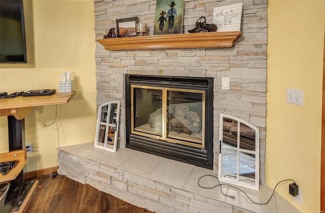 room details featuring a stone fireplace and wood-type flooring