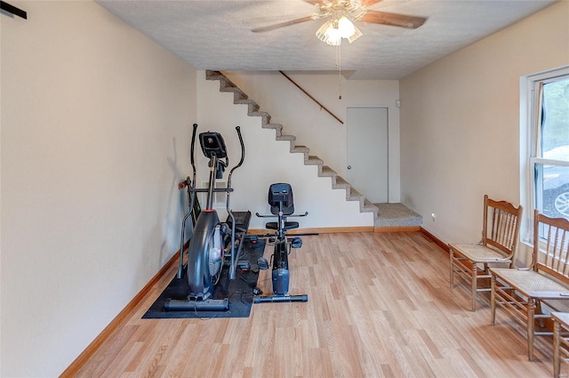 exercise area featuring light hardwood / wood-style flooring, a textured ceiling, and ceiling fan