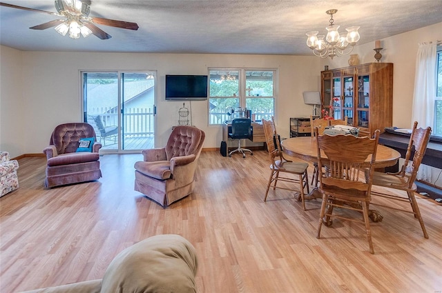 dining space with light hardwood / wood-style flooring, a textured ceiling, and ceiling fan with notable chandelier