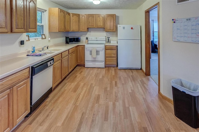 kitchen featuring white appliances, sink, a textured ceiling, and light colored carpet