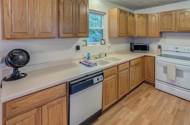 kitchen with white appliances, light wood-type flooring, a textured ceiling, and sink