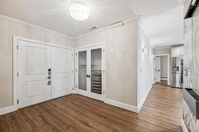 foyer entrance with dark hardwood / wood-style floors, french doors, and ornamental molding