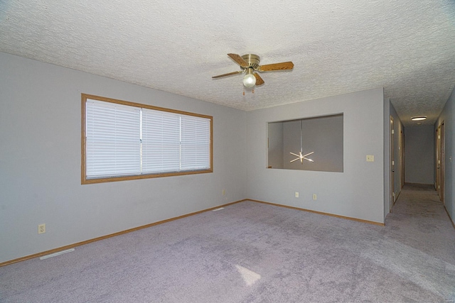 unfurnished room with a textured ceiling, ceiling fan, and light carpet