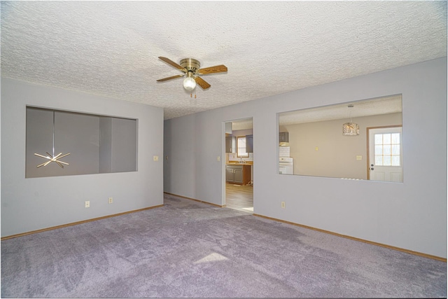 carpeted spare room featuring a textured ceiling and ceiling fan with notable chandelier