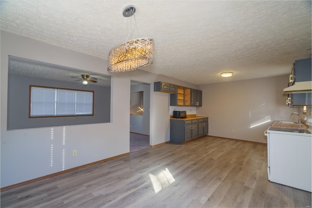 kitchen featuring sink, hanging light fixtures, wood-type flooring, a textured ceiling, and ceiling fan with notable chandelier