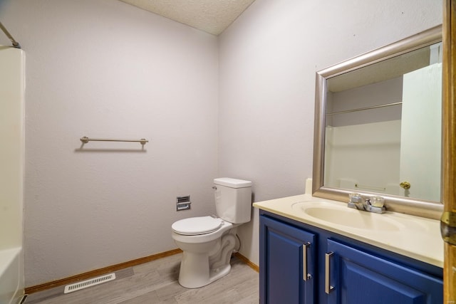 bathroom with vanity, wood-type flooring, a textured ceiling, and toilet