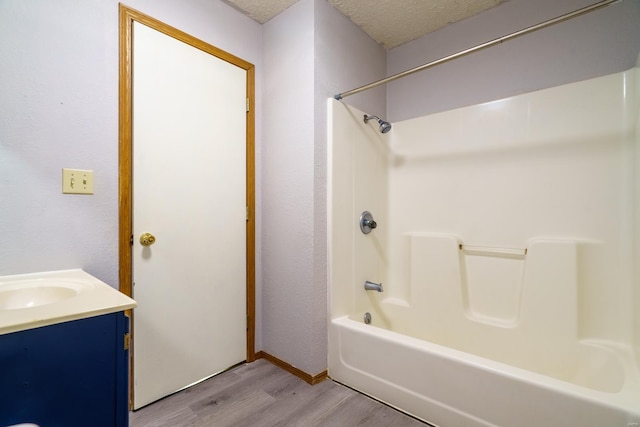 bathroom featuring vanity, hardwood / wood-style floors, a textured ceiling, and bathing tub / shower combination