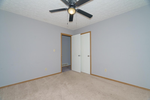 spare room featuring light carpet, ceiling fan, and a textured ceiling