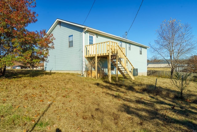 rear view of property with cooling unit, a yard, and a wooden deck