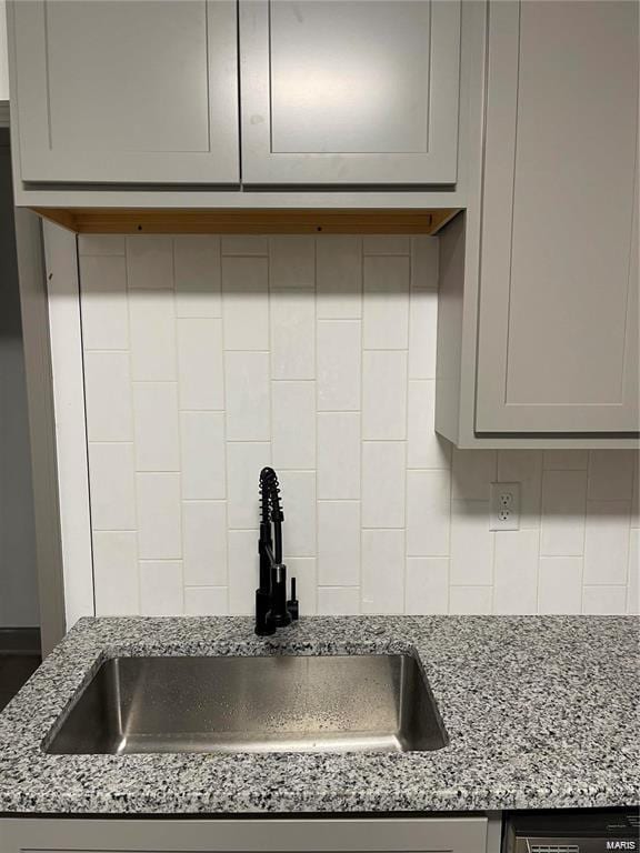 kitchen featuring sink, gray cabinetry, light stone countertops, and tasteful backsplash