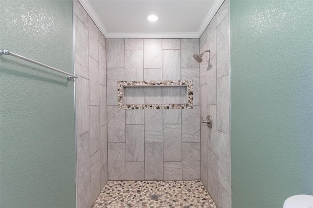 bathroom with a tile shower and crown molding