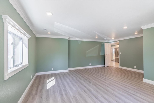 empty room with ornamental molding and light hardwood / wood-style floors