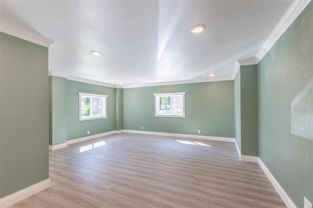 spare room featuring crown molding, plenty of natural light, and light hardwood / wood-style floors