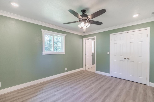 unfurnished bedroom featuring ceiling fan, ornamental molding, a closet, and light wood-type flooring