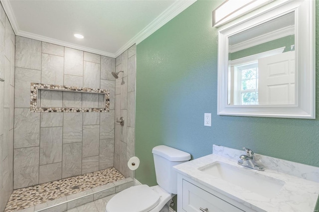 bathroom with vanity, crown molding, toilet, and tiled shower