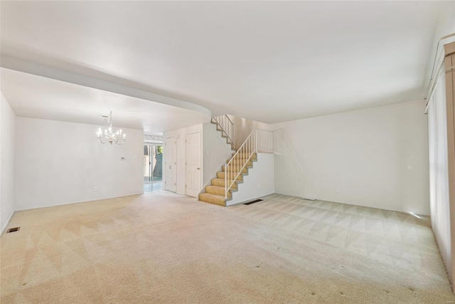 unfurnished living room with light carpet and a notable chandelier