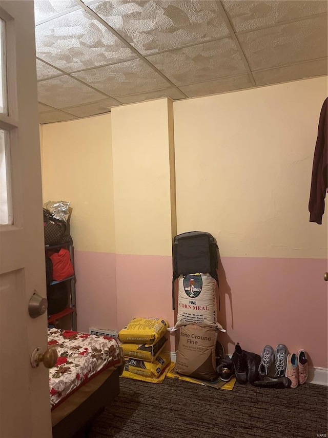 carpeted bedroom featuring a drop ceiling