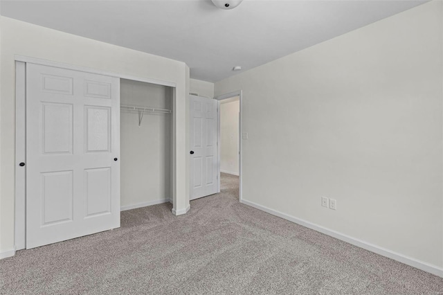 unfurnished bedroom featuring light carpet and a closet