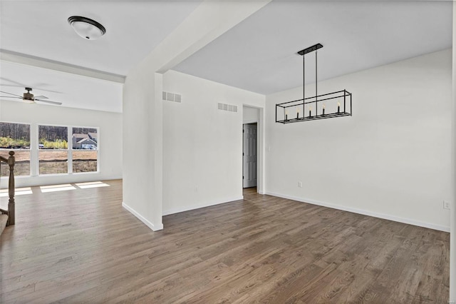 unfurnished dining area featuring a ceiling fan, visible vents, baseboards, and wood finished floors