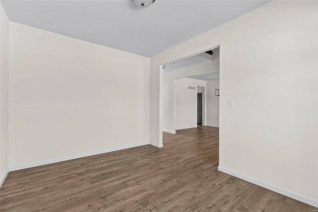 spare room featuring baseboards and wood finished floors