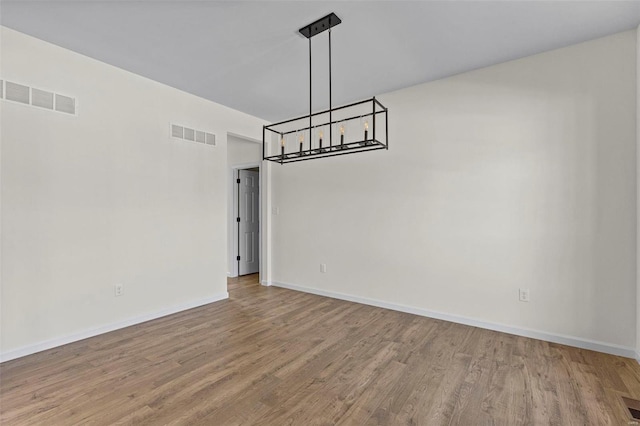 unfurnished room with visible vents, baseboards, and wood finished floors