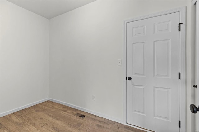 spare room featuring light wood-style floors, visible vents, and baseboards