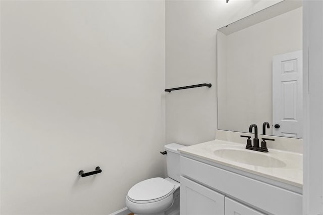 half bath with baseboards, vanity, and toilet