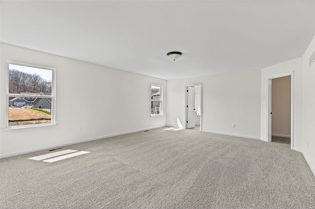 spare room with carpet floors, visible vents, and baseboards