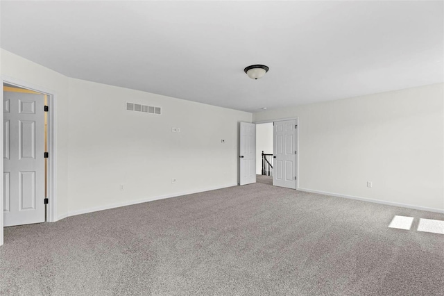 spare room featuring carpet floors, baseboards, and visible vents