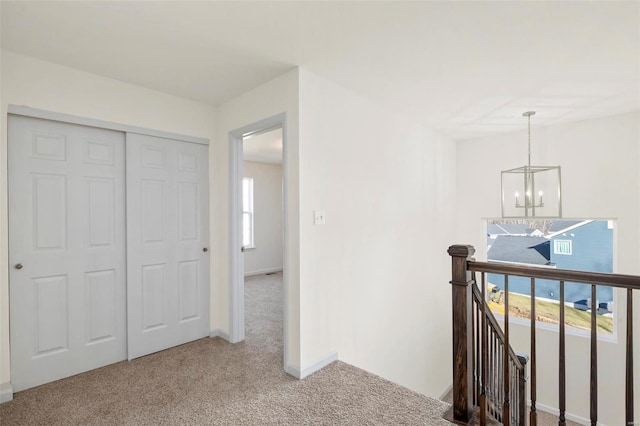 hallway featuring light colored carpet and an inviting chandelier