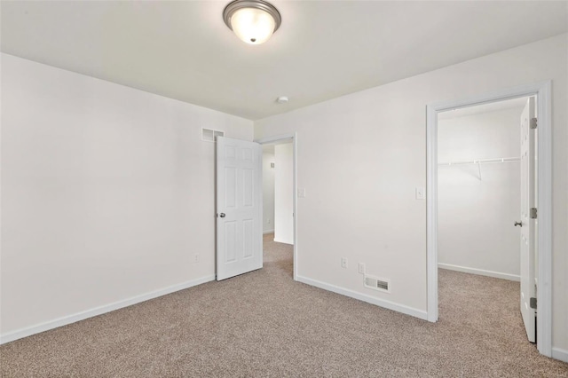 unfurnished bedroom with light colored carpet, a spacious closet, and a closet