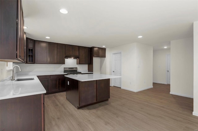 kitchen with dark brown cabinetry, a center island, sink, light hardwood / wood-style flooring, and stainless steel range oven