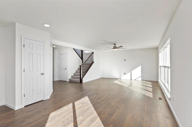 unfurnished living room featuring ceiling fan and dark wood-type flooring