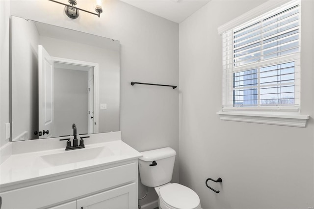 bathroom with toilet, vanity, and a healthy amount of sunlight