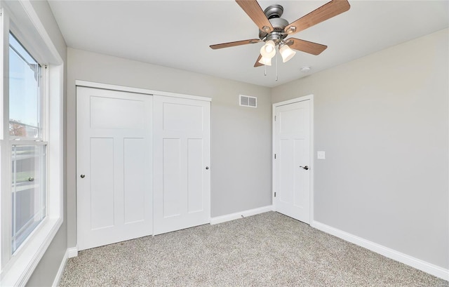 unfurnished bedroom featuring light colored carpet, ceiling fan, and a closet