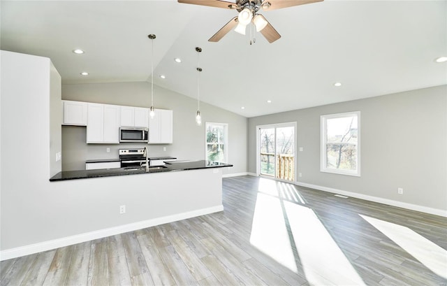 kitchen with sink, stainless steel appliances, white cabinets, decorative light fixtures, and dark stone counters