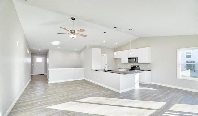 kitchen featuring white cabinetry, sink, hanging light fixtures, stainless steel appliances, and light wood-type flooring