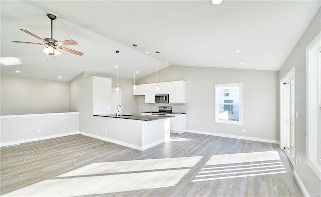 kitchen with pendant lighting, sink, white cabinets, stainless steel appliances, and light wood-type flooring