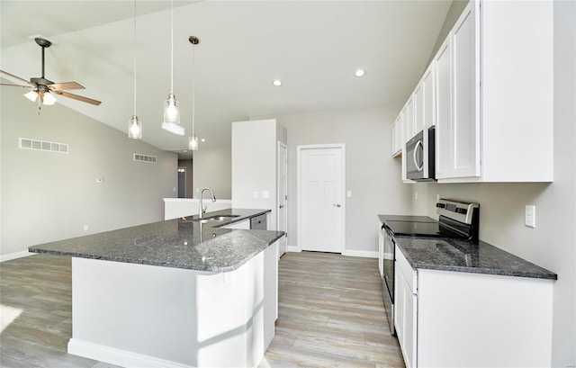 kitchen featuring white cabinetry, light hardwood / wood-style flooring, appliances with stainless steel finishes, pendant lighting, and dark stone counters