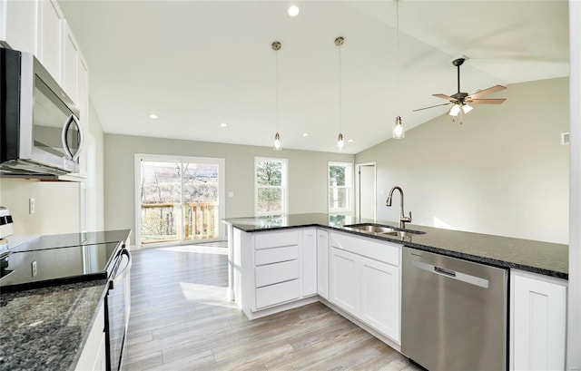 kitchen with appliances with stainless steel finishes, sink, white cabinets, dark stone counters, and hanging light fixtures