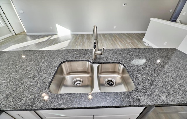 interior details with sink, dark stone countertops, and white cabinets