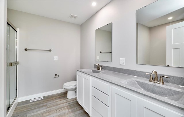 bathroom featuring vanity, toilet, an enclosed shower, and hardwood / wood-style floors