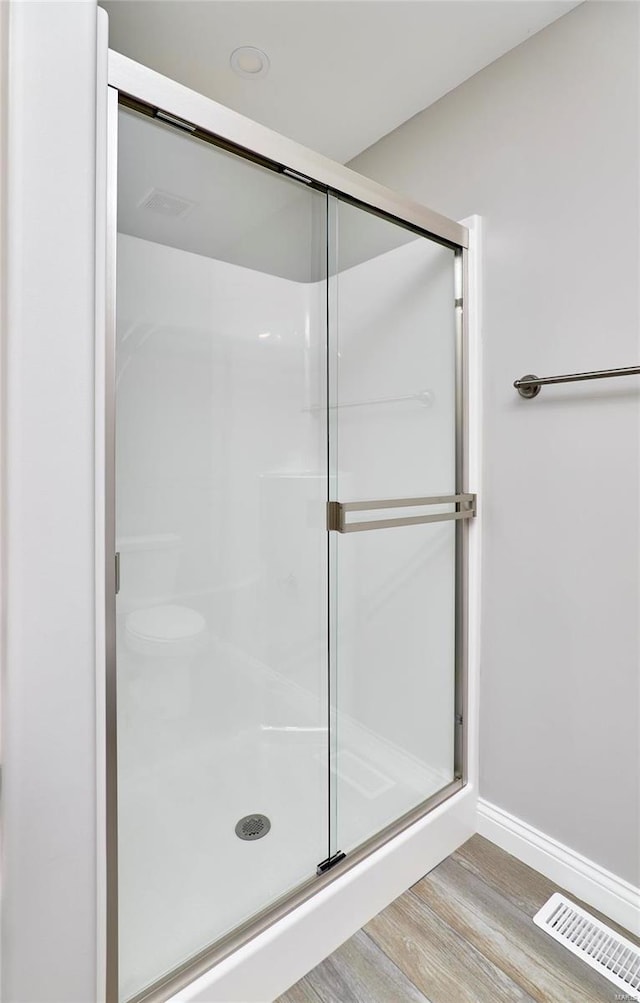 bathroom with hardwood / wood-style flooring and an enclosed shower