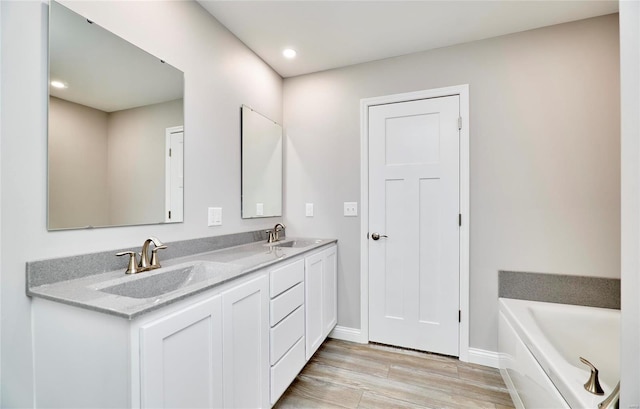 bathroom with vanity, wood-type flooring, and a bath