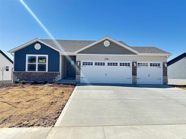 view of front facade with brick siding, a shingled roof, concrete driveway, an attached garage, and board and batten siding